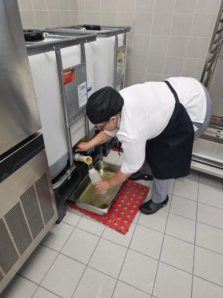 Cocinera rellenando un biberón de aceite de un IBC